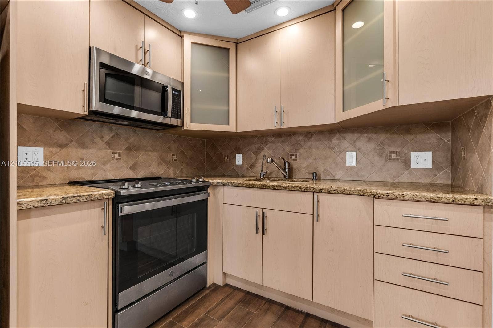 222 Tilford A, #222, Deerfield Beach, FL 33442 Kitchen featuring light wood-finish cabinetry, stainless steel appliances, granite countertops, and a tiled backsplash