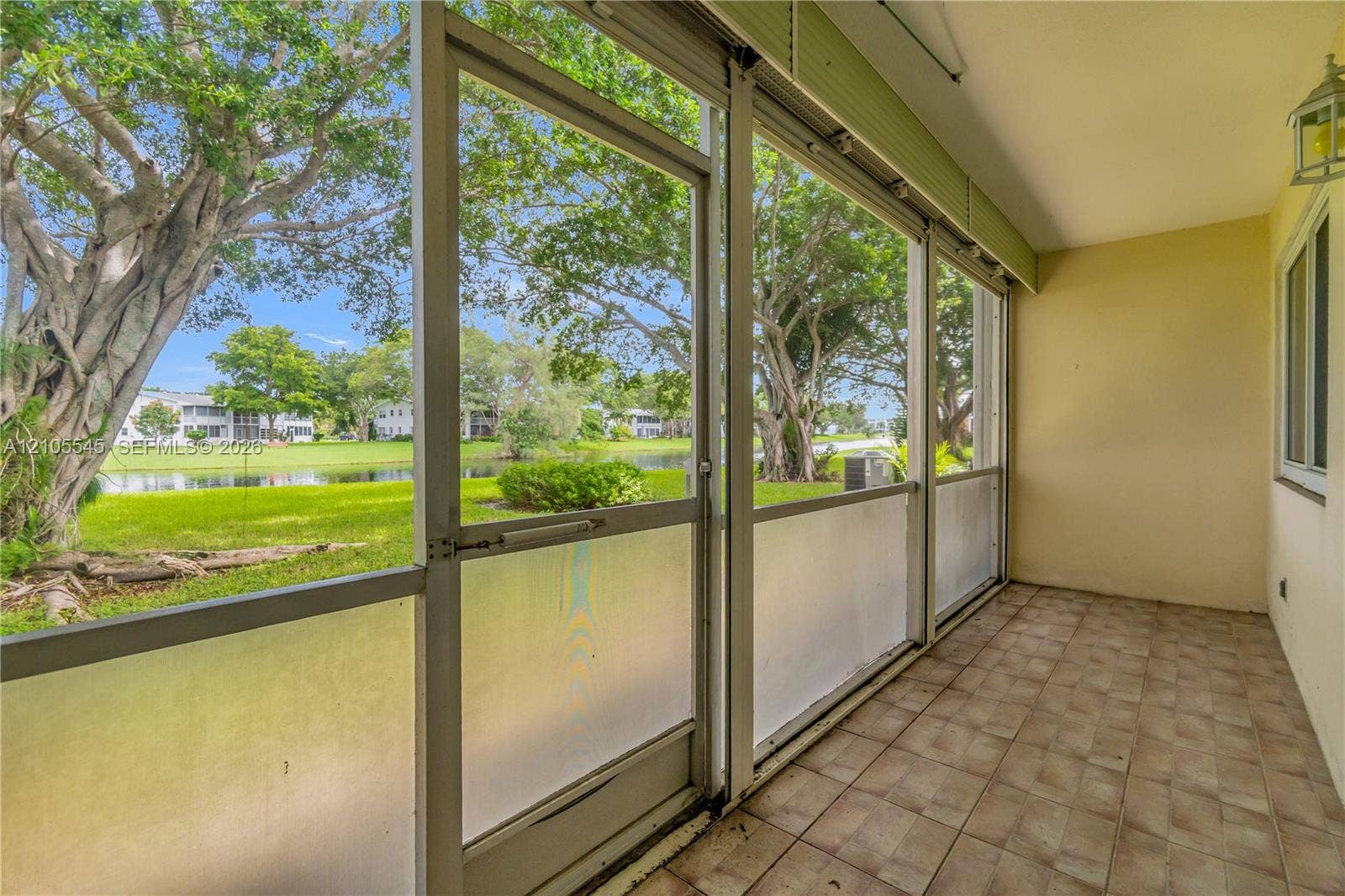 222 Tilford A, #222, Deerfield Beach, FL 33442 Screened patio with tiled flooring, featuring a wall-mounted lantern light fixture