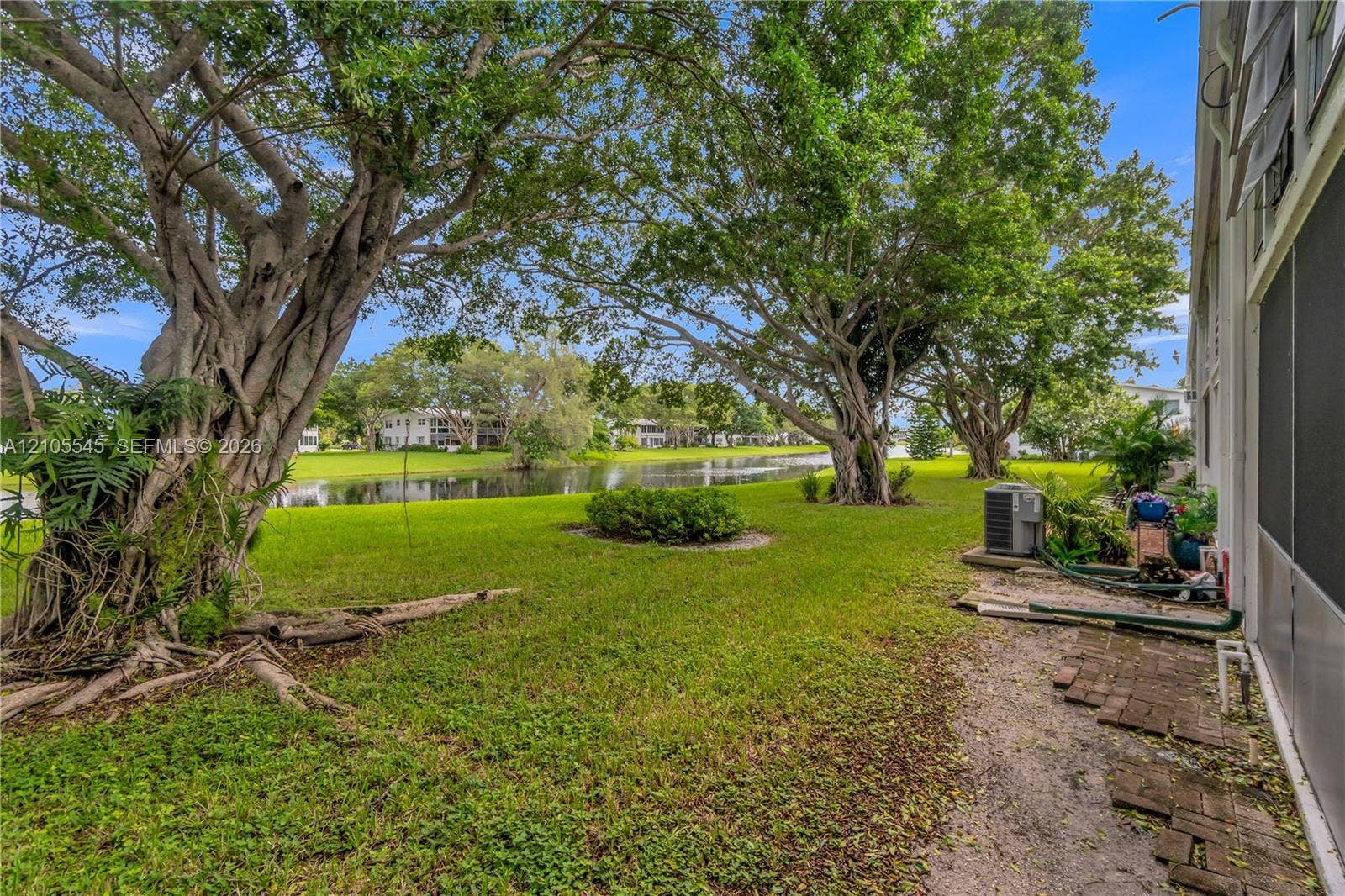 222 Tilford A, #222, Deerfield Beach, FL 33442 Expansive green lawn with mature trees, a tranquil canal, and distant residential structures