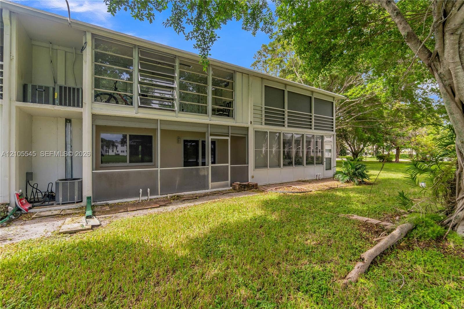 222 Tilford A, #222, Deerfield Beach, FL 33442 Multi-level property featuring screened enclosures, large jalousie windows, and a generous grassy area