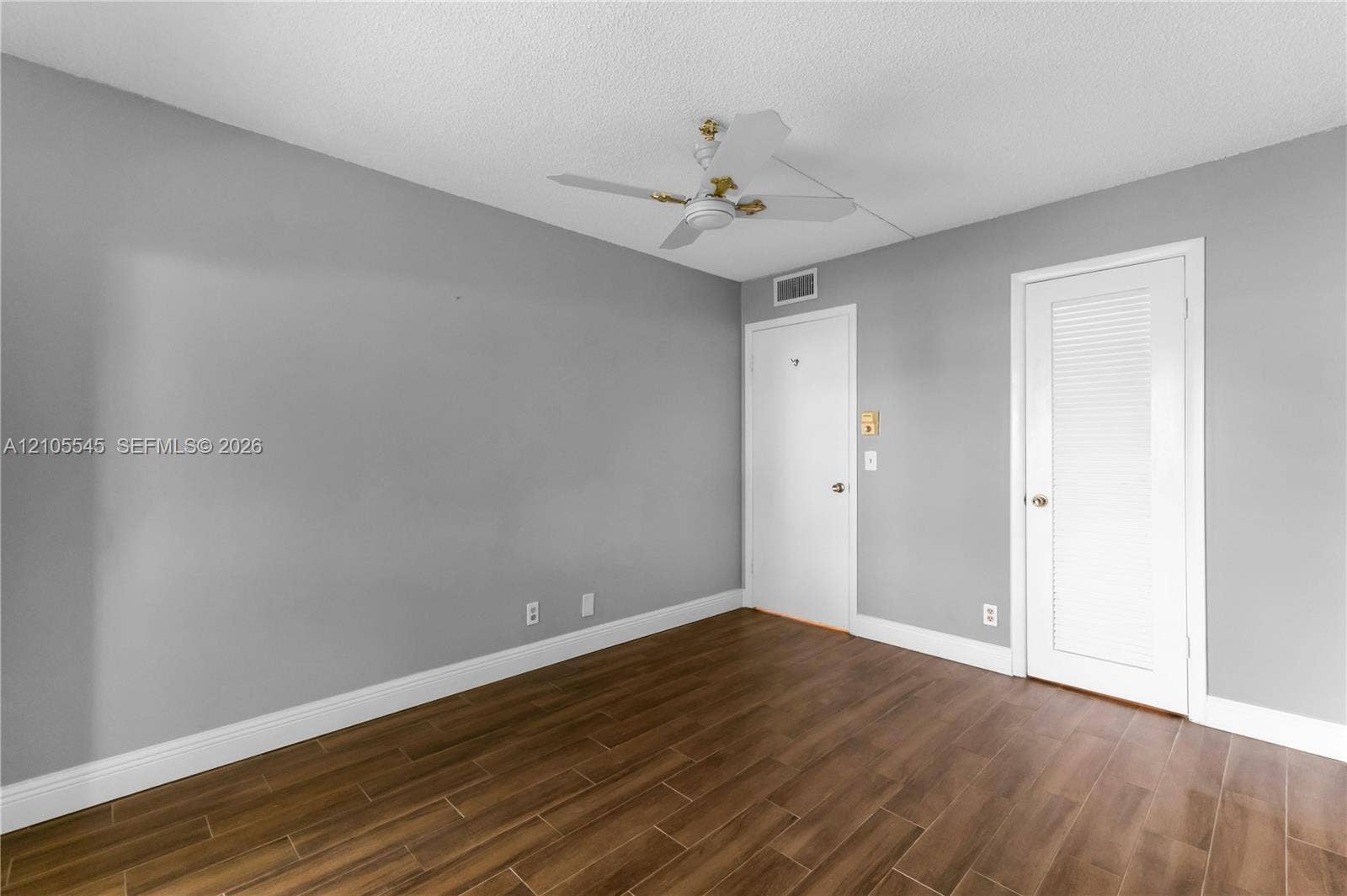 222 Tilford A, #222, Deerfield Beach, FL 33442 Wood-finish ceramic flooring, white baseboards, ceiling fan with light fixture, and two white doors with hardware