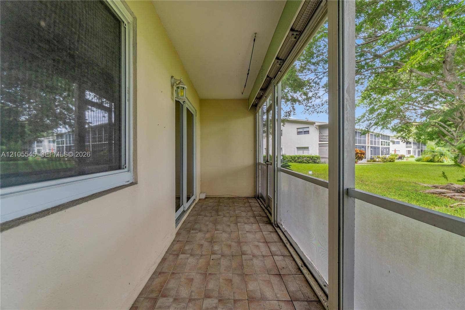 222 Tilford A, #222, Deerfield Beach, FL 33442 Screened patio with tiled flooring and exterior lighting fixture