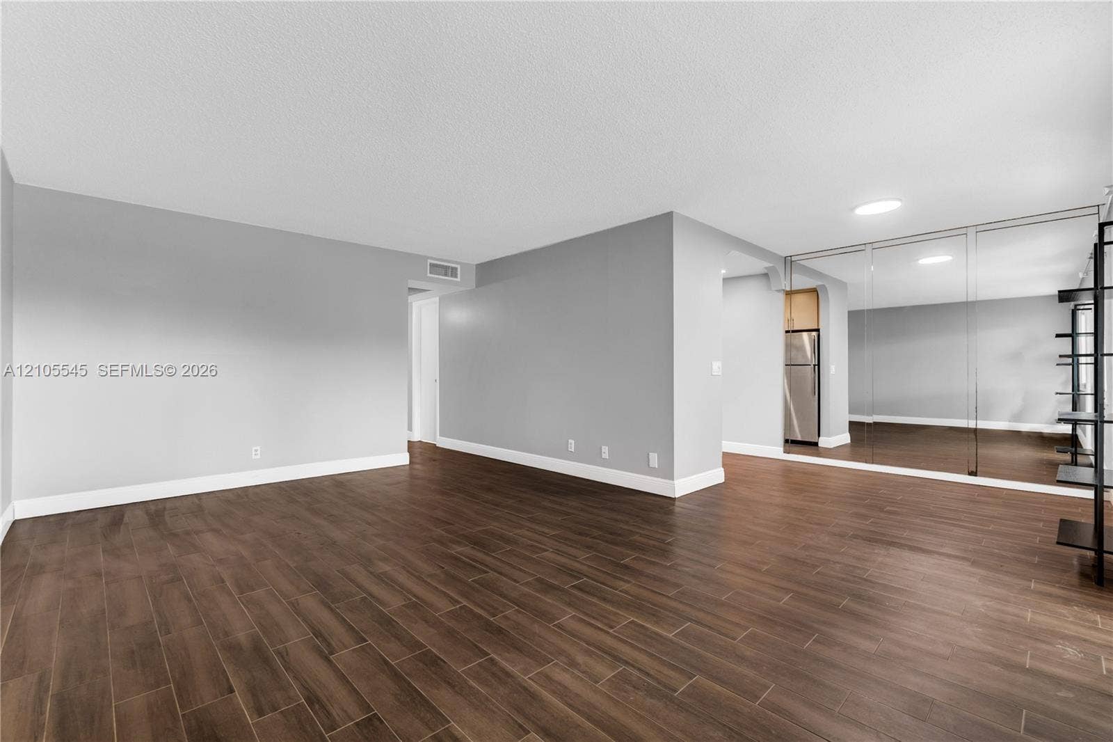 222 Tilford A, #222, Deerfield Beach, FL 33442 Spacious open-concept room featuring wood-finish tile flooring, light gray wall paint, and full wall mirrors