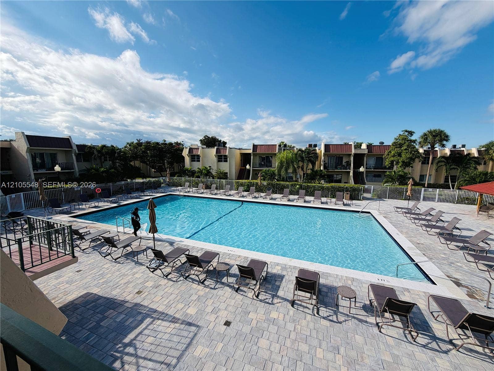 Large olympic size swimming pool with paved deck and perimeter fencing