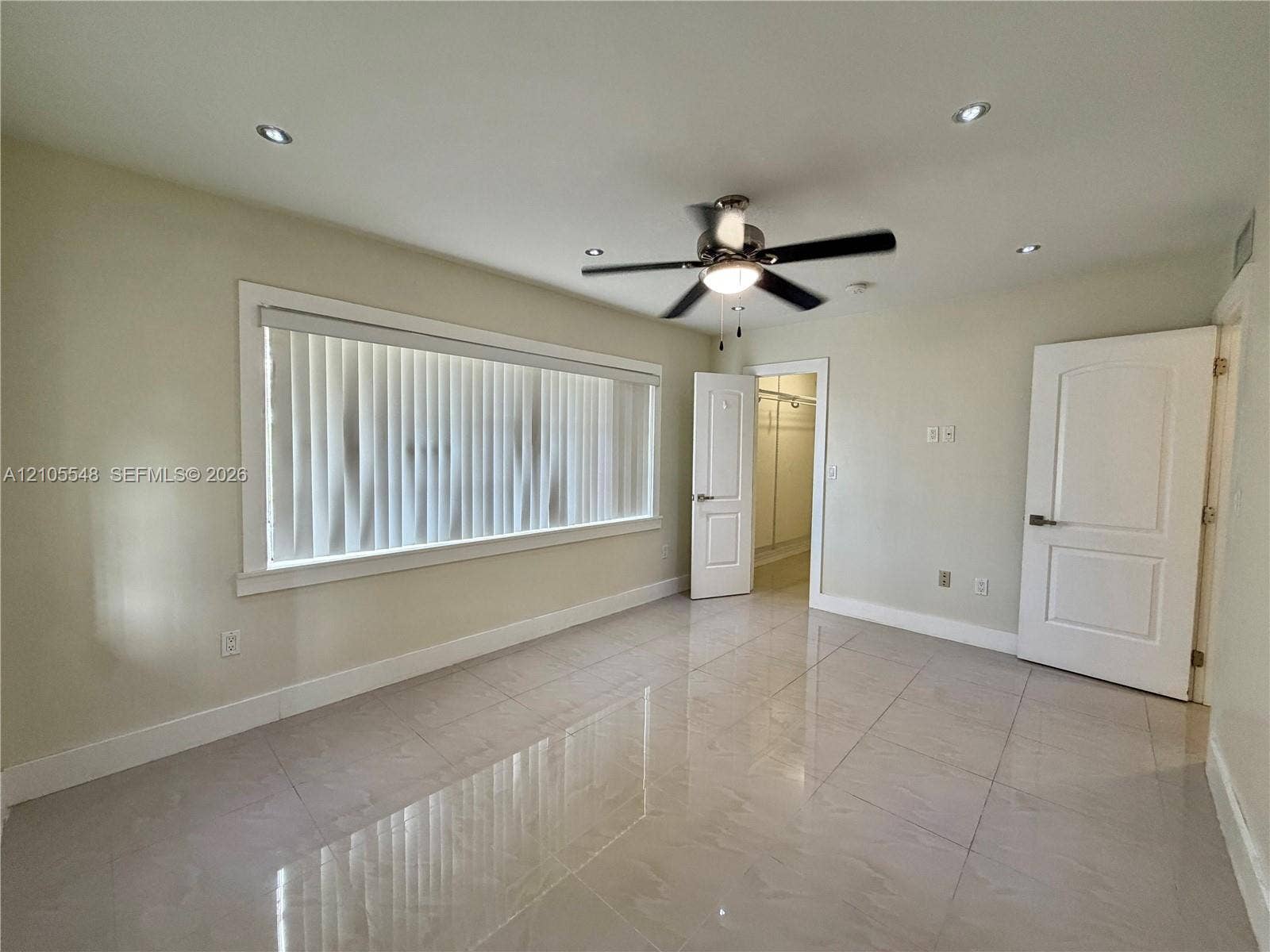 Spacious room featuring polished porcelain tile flooring, recessed lighting, a ceiling fan with integrated light fixture, and two panel-style doors