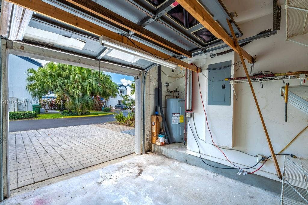 Garage interior with water heater, electrical panel, and fluorescent lighting