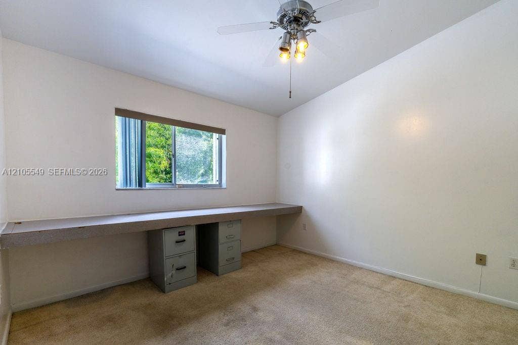 Recessed window with horizontal blinds, built-in desk counter, and ceiling fan with integrated lighting
