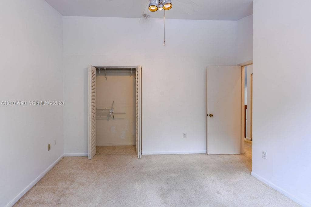 Carpeted flooring, white walls, bi-fold closet doors, integrated ceiling light fixture, interior door with brass hardware