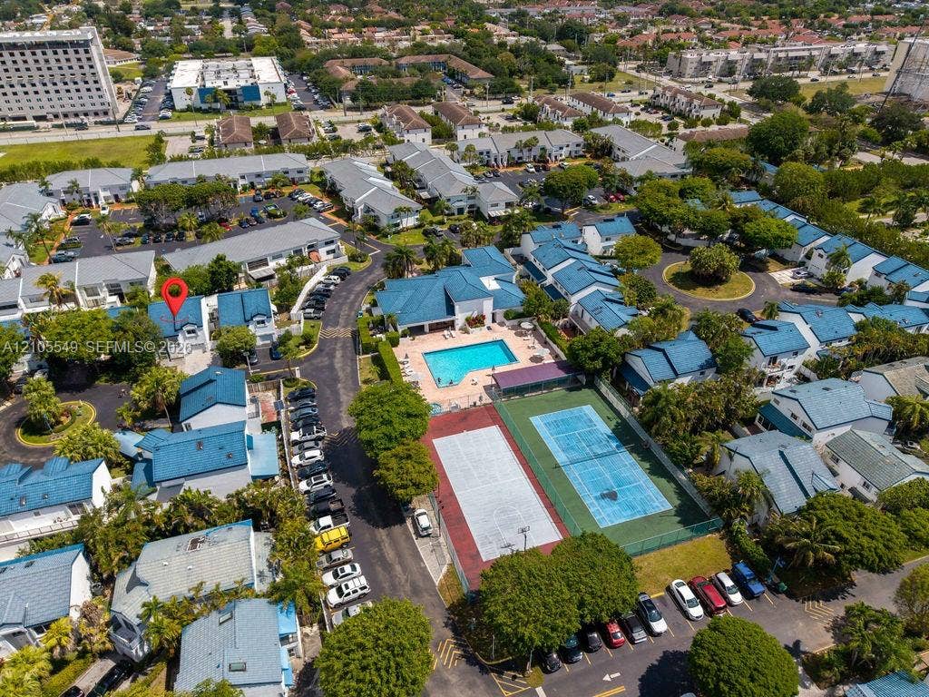 Community setting featuring multiple residential buildings with blue roofs, a swimming pool, and a tennis court