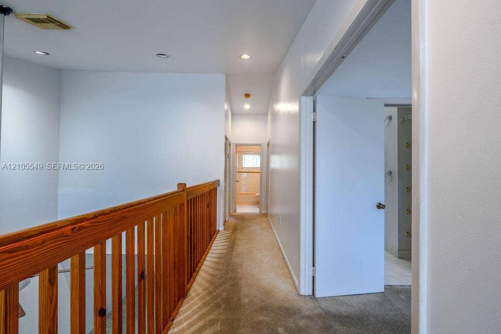 Hallway with recessed lighting, wood railing, and carpet flooring