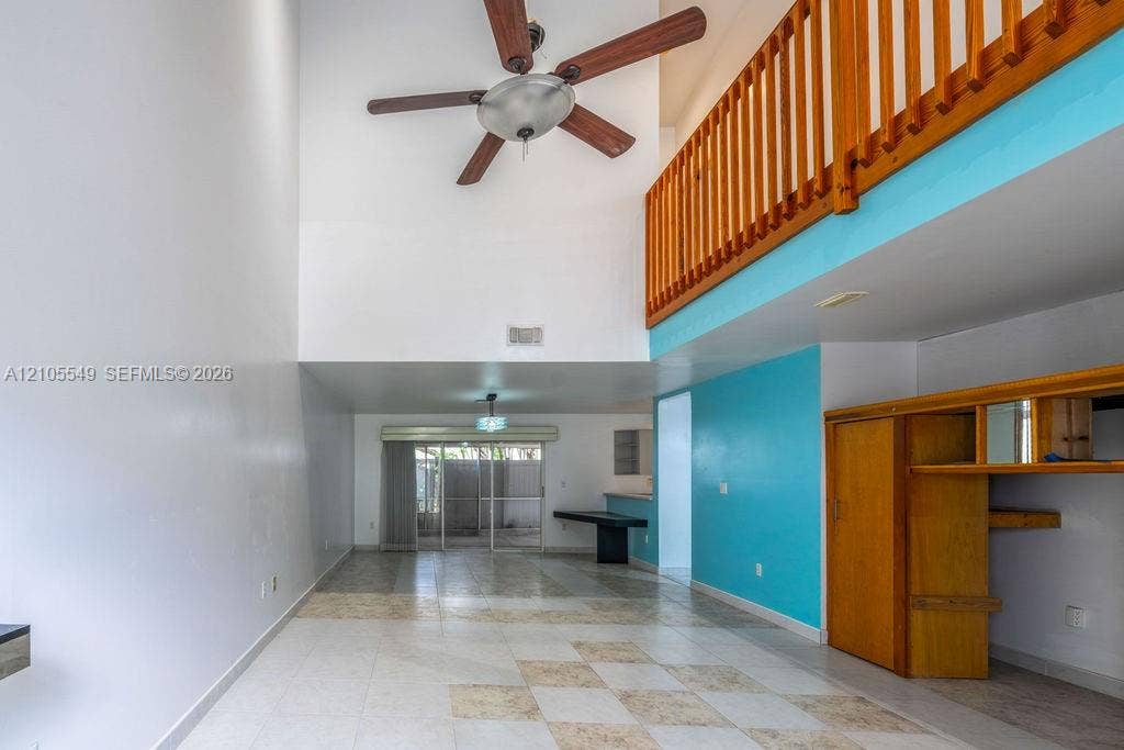 Two-story interior featuring an open wood-finish railing, a ceiling fan, and checkered floor tiling