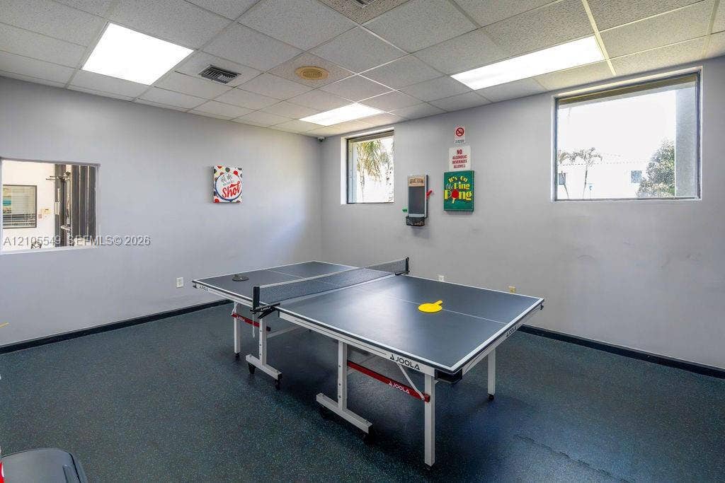 Recessed ceiling lights, acoustic ceiling tiles, two large windows, and resilient flooring