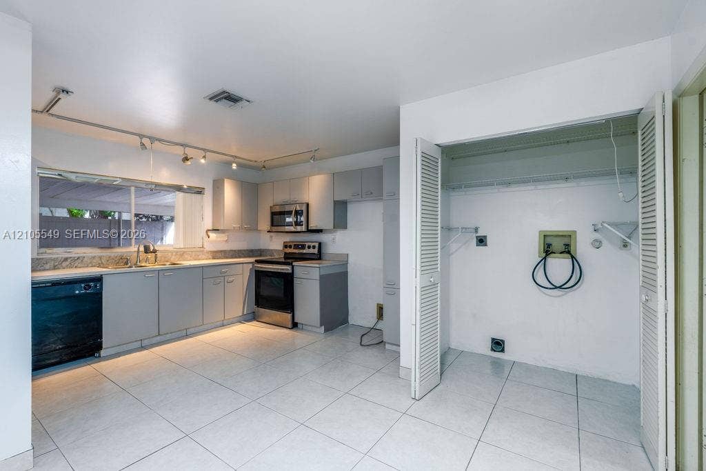Kitchen area featuring light-toned cabinetry, stainless steel microwave, electric range, and dishwasher