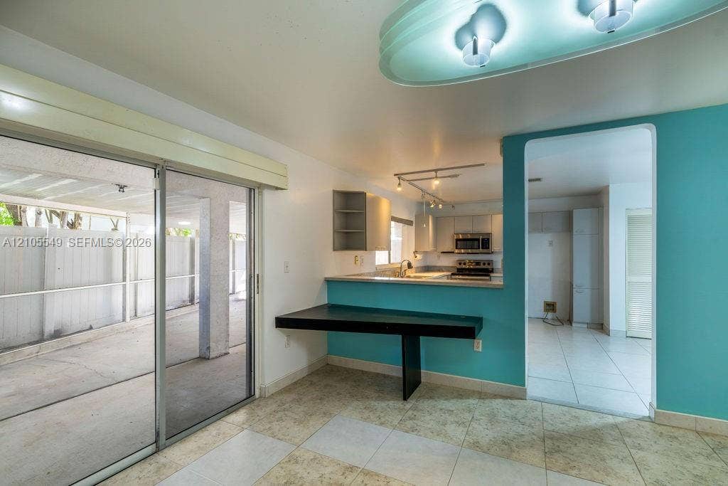Sliding glass doors, tiled flooring, built-in desk, kitchen pass-through, and modern light fixture