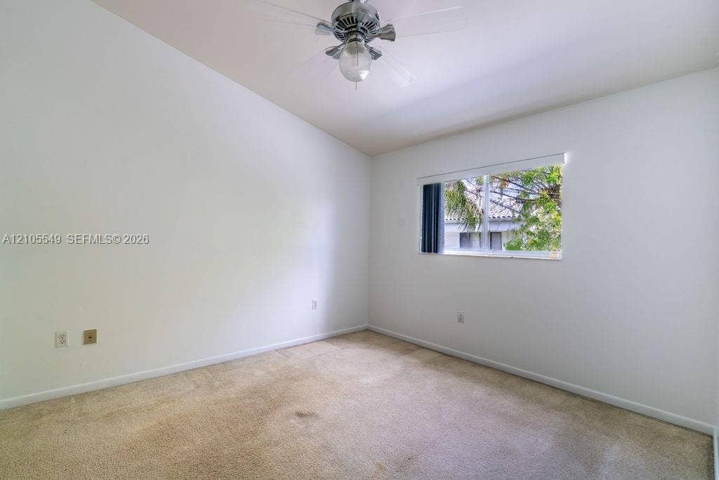 Vaulted ceiling, ceiling fan, carpet flooring, single window, and light-colored walls
