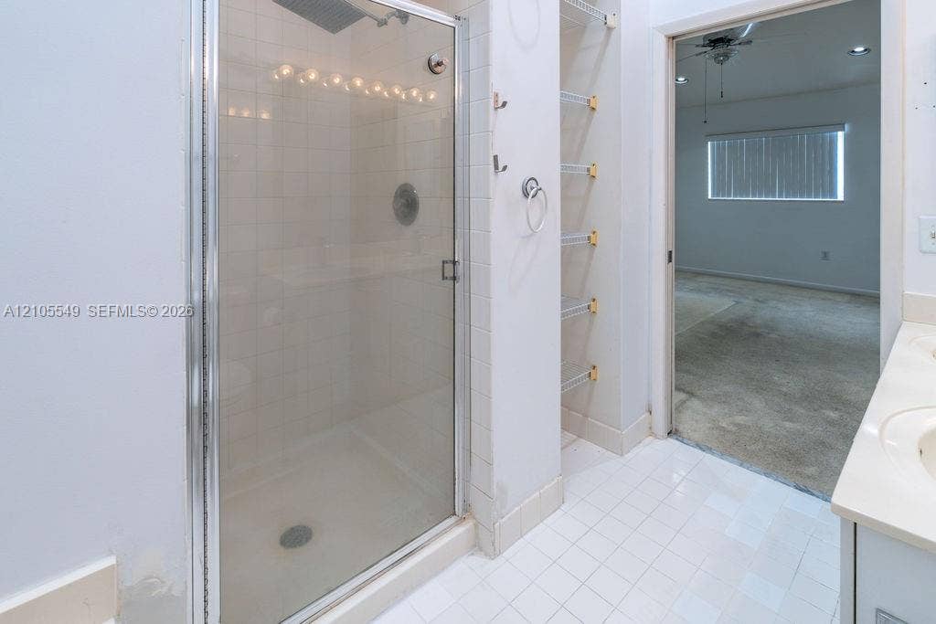 Walk-in shower with clear glass enclosure and overhead lighting