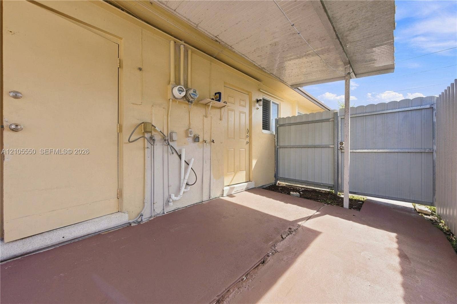Covered patio with concrete flooring, utility access, and secure privacy fencing