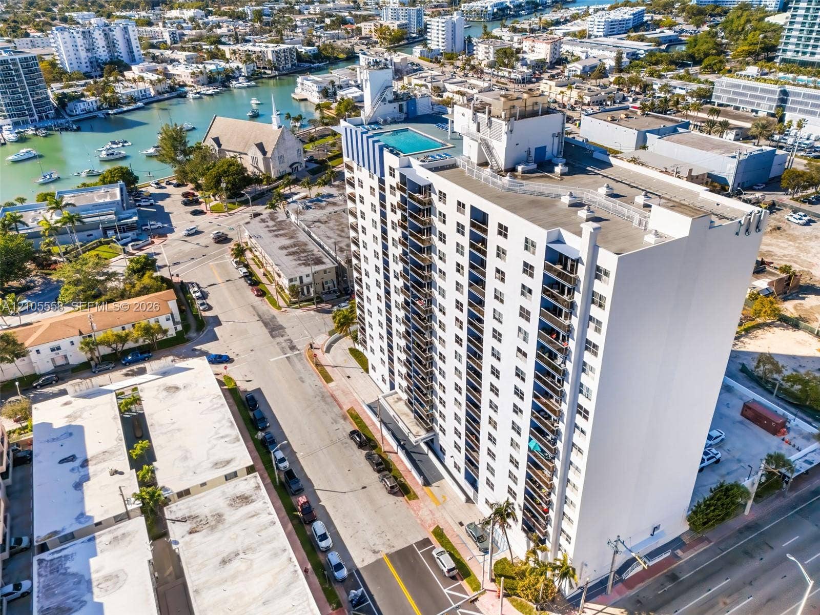 High-rise building featuring multiple balconies, a rooftop pool, and surrounding urban streets