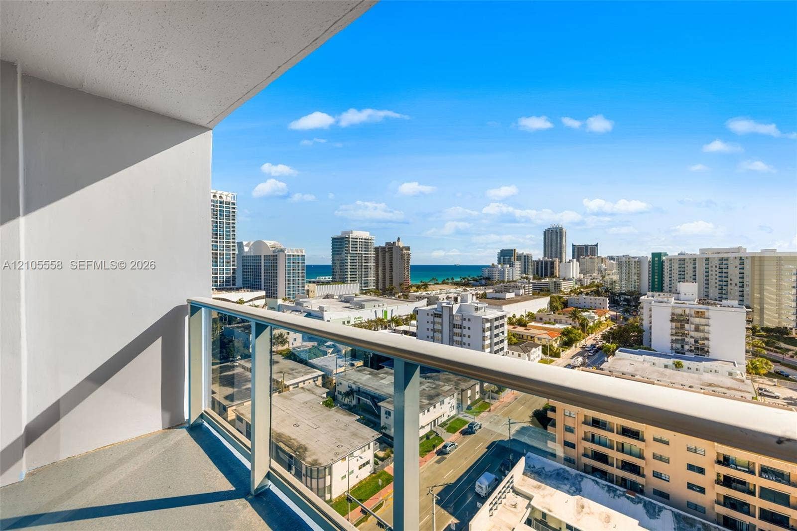Balcony with glass railing, urban scenery, and distant ocean