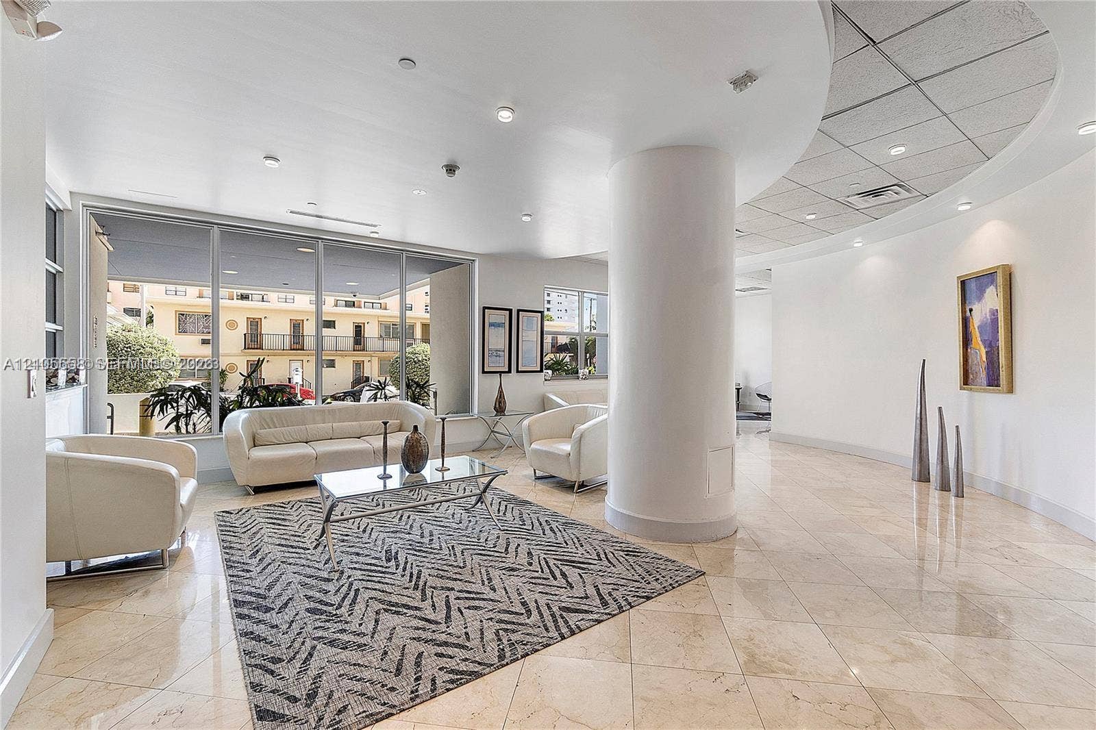 Expansive interior space featuring large format stone tile flooring, recessed lighting, a curved architectural column, and extensive glass paneling