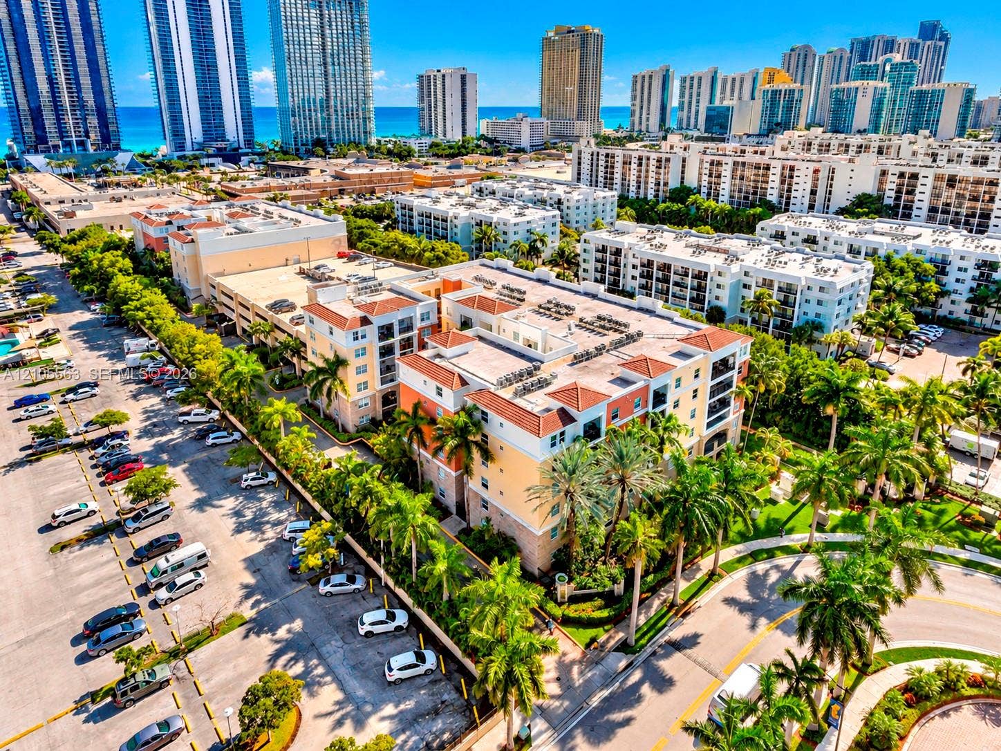 17145 N Bay Road, #4613, Sunny Isles Beach, Sunny Isles Beach, FL 33160 Multi-story building with a terracotta-style roof, surrounded by mature palm trees