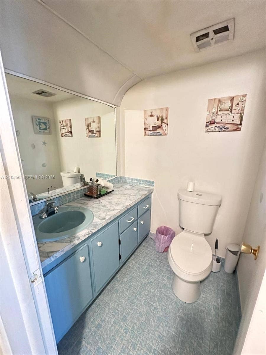 Vanity with light blue cabinetry, built-in sink, and patterned countertop