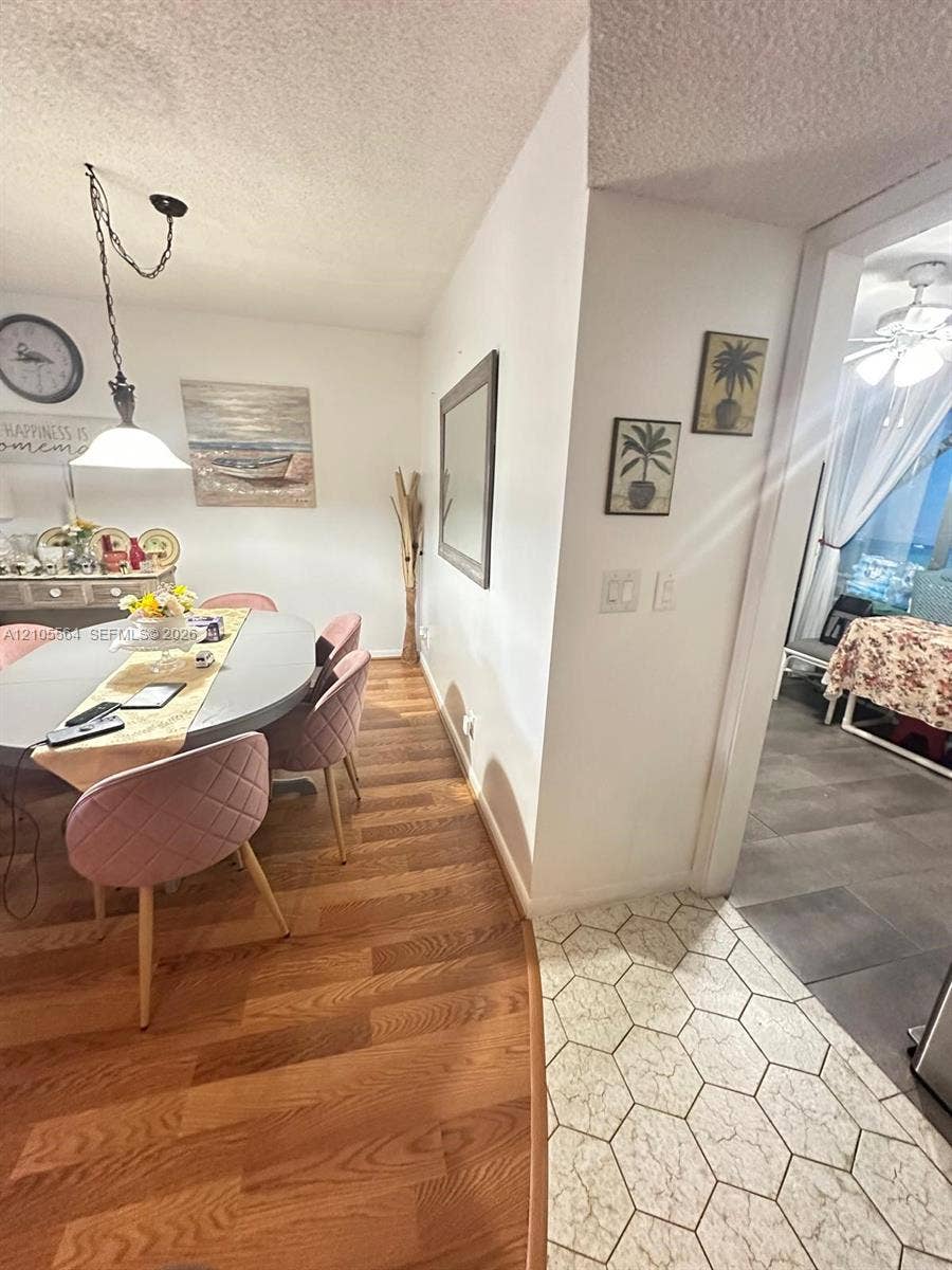 Wood-finish flooring, white walls, and a hanging pendant light fixture