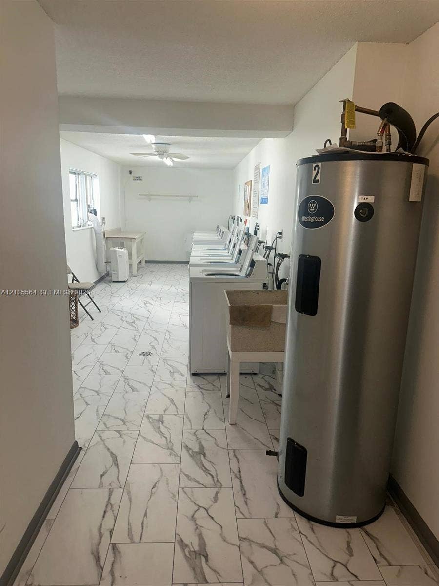 Marbled tile flooring, white walls, ceiling fan, and multiple washing machines