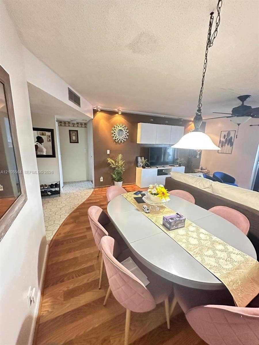 Wood-finish flooring, recessed lighting, and a partial hallway with patterned floor tiles