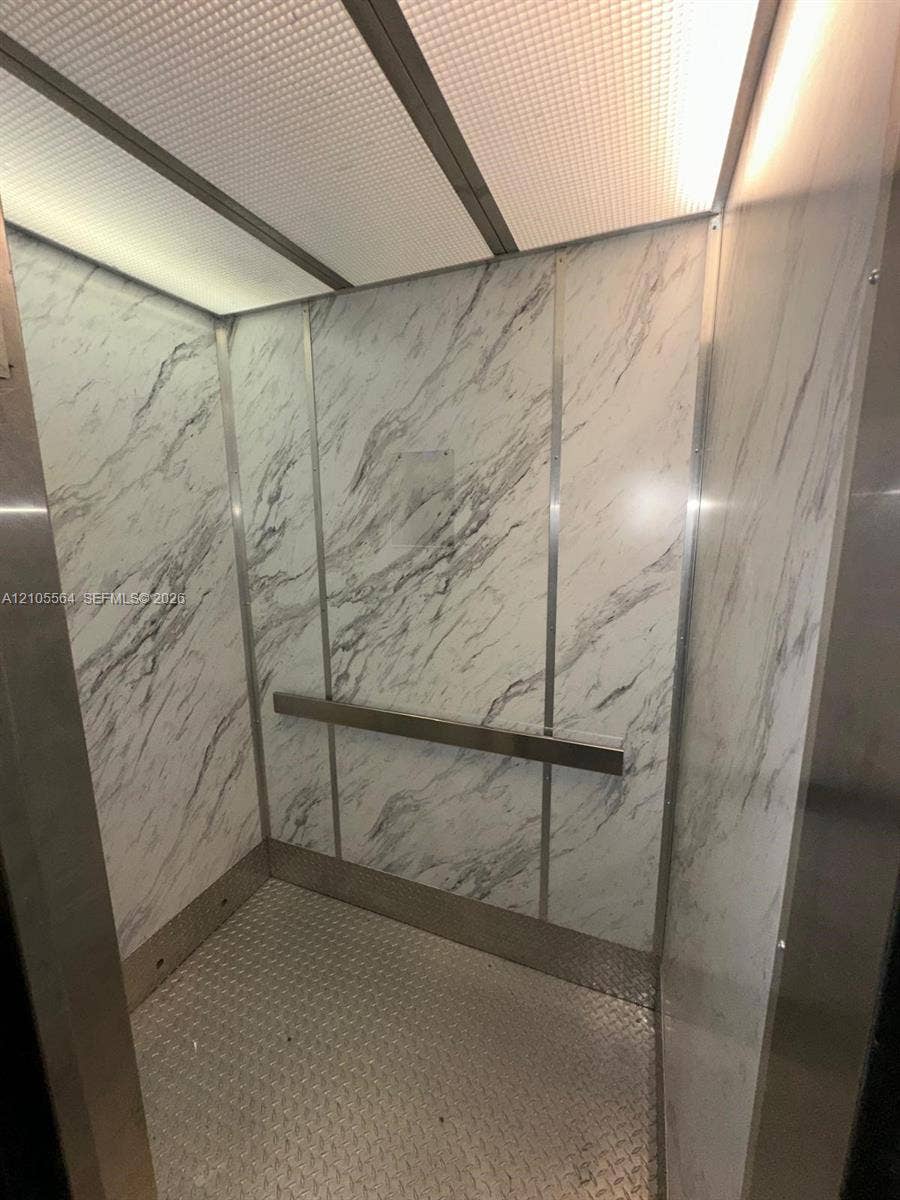 White marble-patterned paneling, brushed metal accents, checker plate flooring, and integrated ceiling lighting