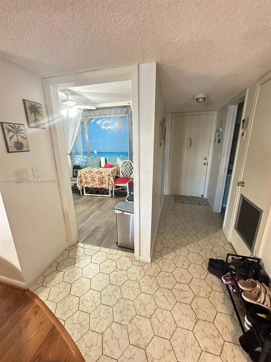 Hexagonal floor tile entry leading to a screened-in balcony with water scenery and wood-finish flooring