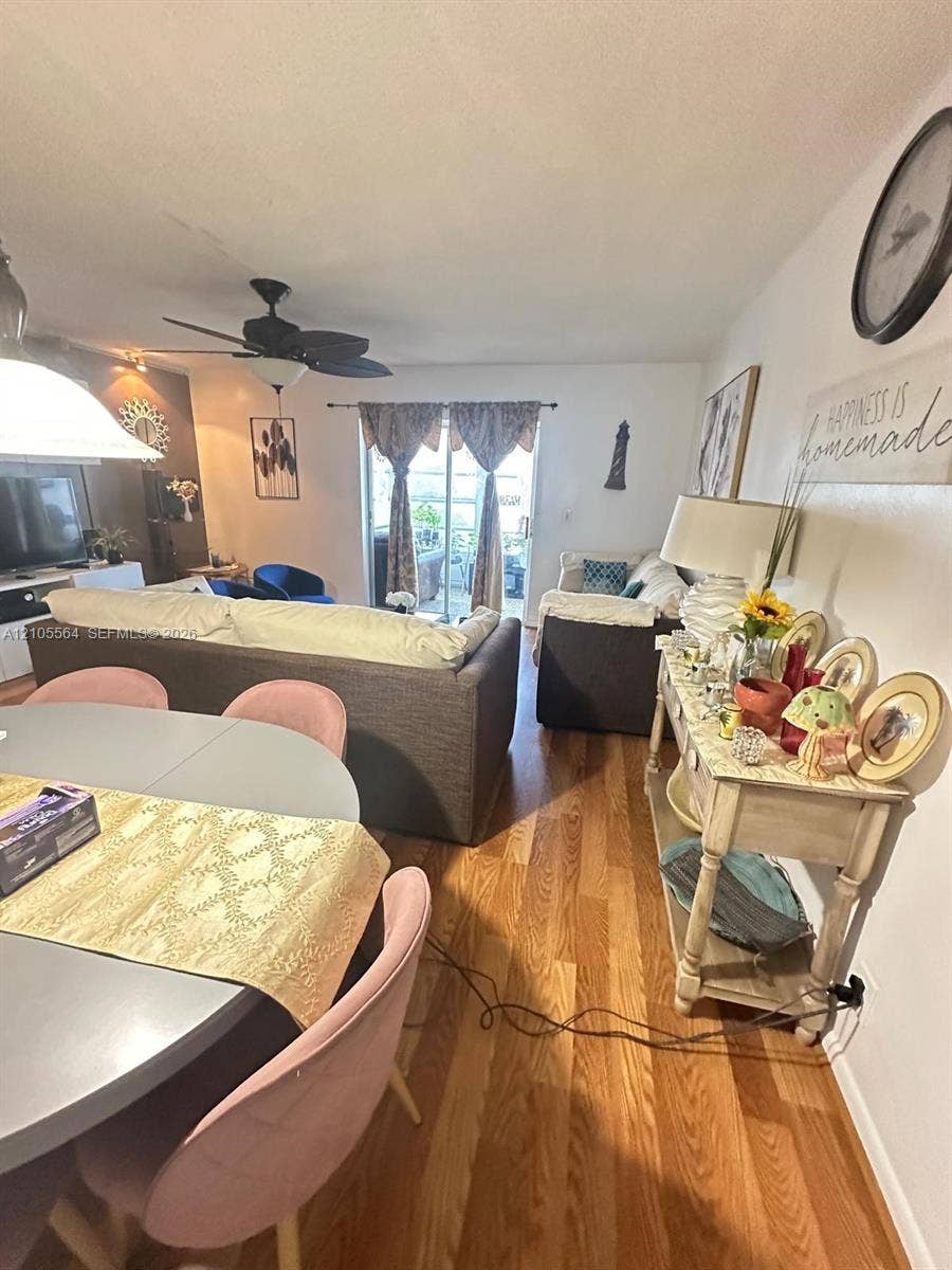 Wood-finish flooring throughout, ceiling fan with integrated lighting, and a glass sliding door providing access to exterior space