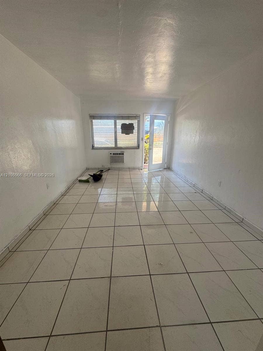 Tile flooring, white walls, and a window air conditioning unit