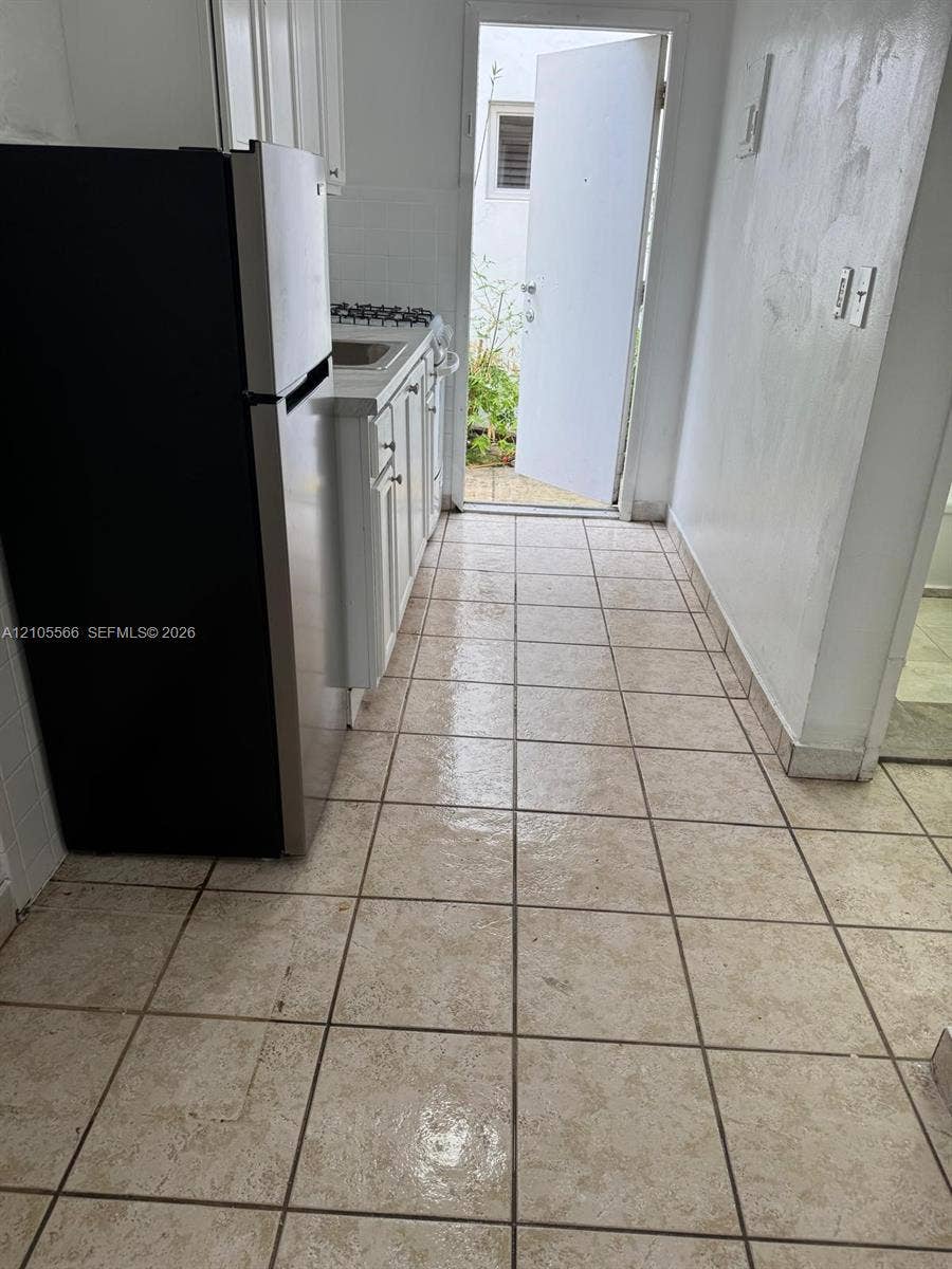 Tile flooring, white cabinetry, integrated sink, stainless steel refrigerator, and built-in stovetop