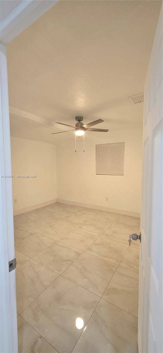 Spacious room featuring large format tile flooring, a ceiling fan with integrated lighting, and a window with blinds