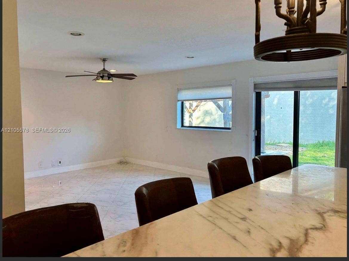 Stone-finish countertop, neutral tile flooring, recessed lighting, ceiling fan with light kit, and sliding glass door