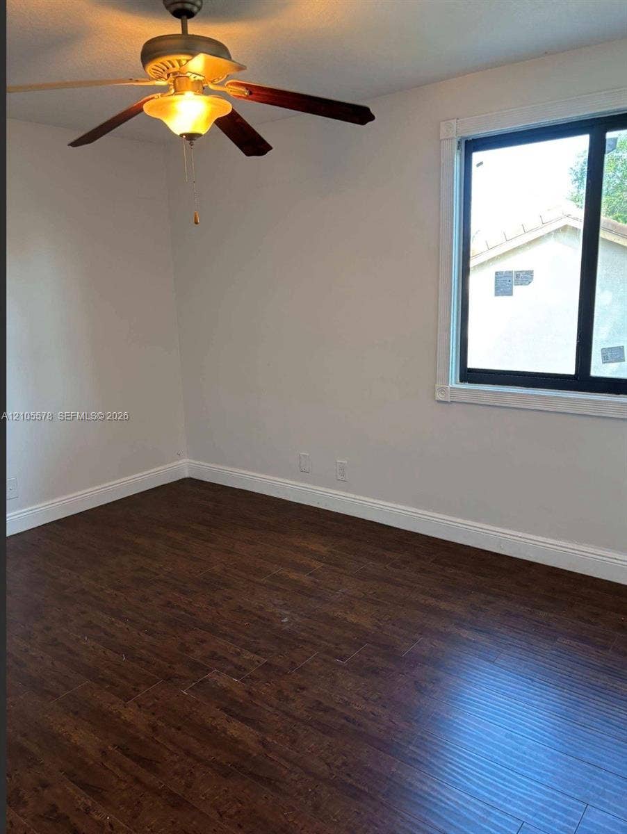 Wood-finish flooring, ceiling fan with integrated lighting, and window with dark trim framing