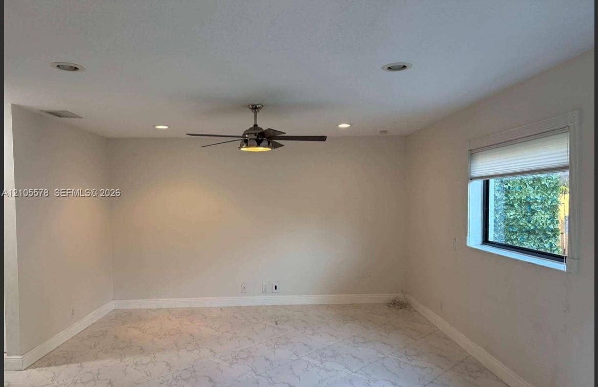 Interior space featuring neutral wall paint, recessed lighting, a ceiling fan with integrated lighting, large-format tile flooring, and a window with a pleated shade