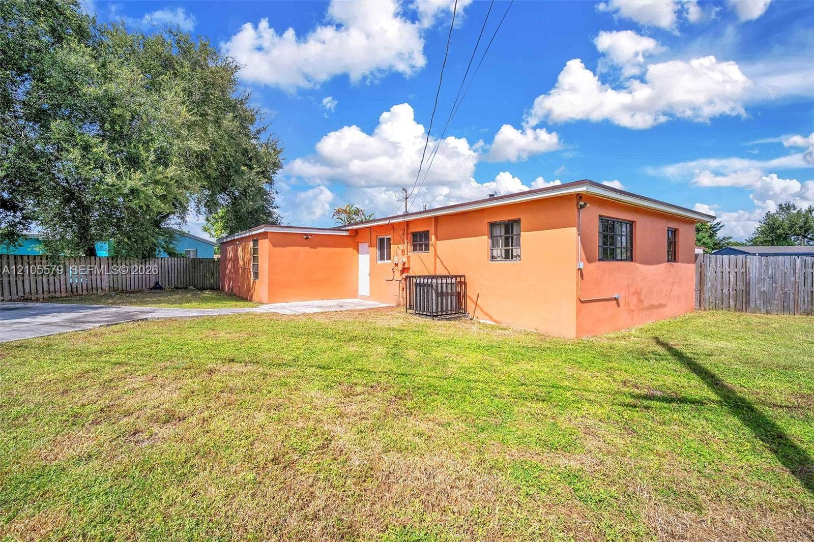 1750 NW 185th Street, Miami Gardens, FL 33056 Stucco exterior with wood-slat privacy fencing and an open lawn area