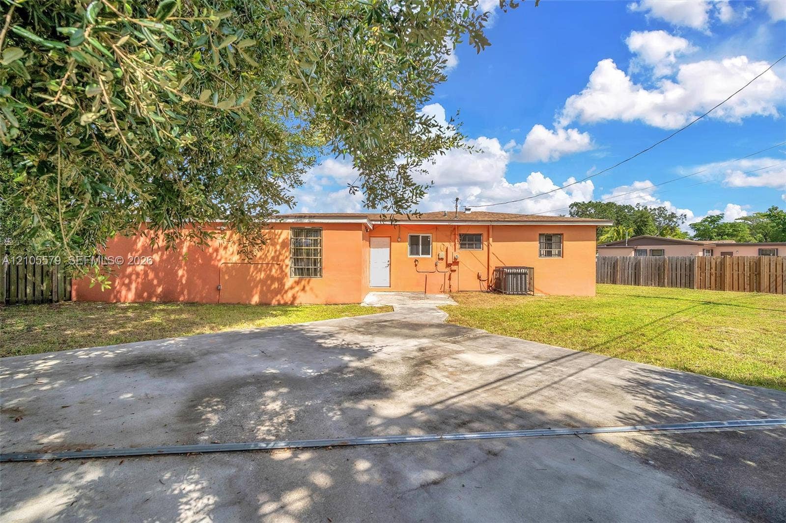 1750 NW 185th Street, Miami Gardens, FL 33056 Exterior of the residence featuring a concrete driveway, masonry walls, horizontal fencing, and a concrete patio