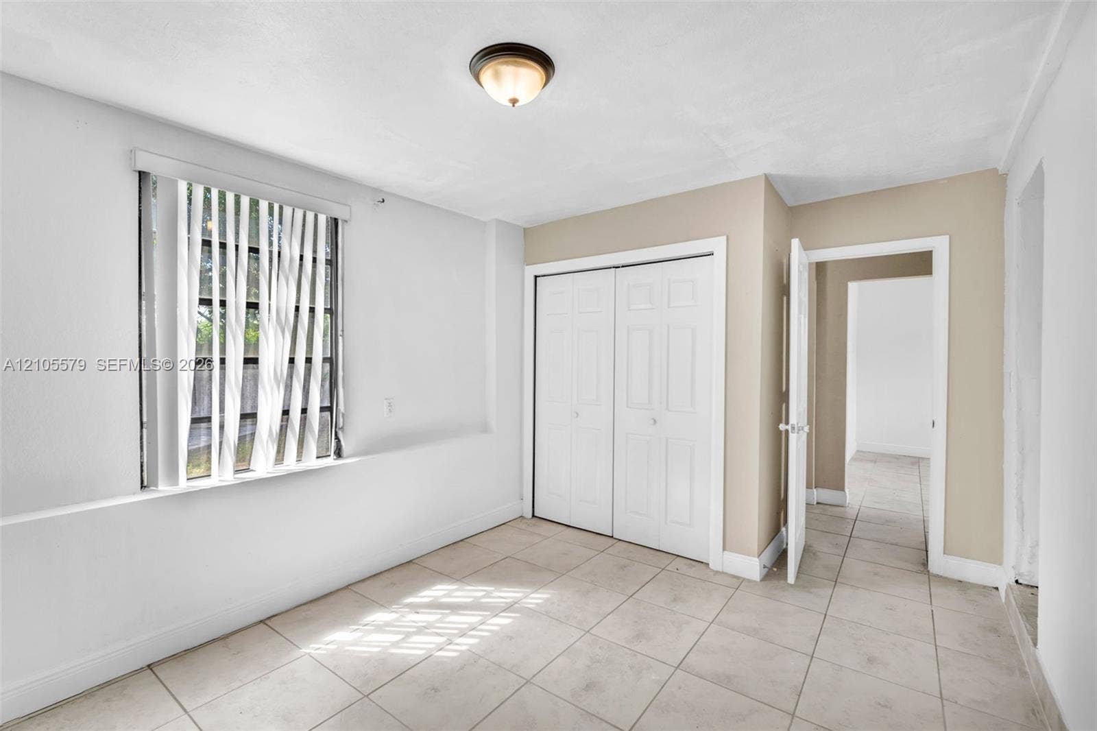 1750 NW 185th Street, Miami Gardens, FL 33056 Neutral-toned interior featuring large-format tile flooring, a double-door closet with paneled doors, and a ceiling-mounted light fixture
