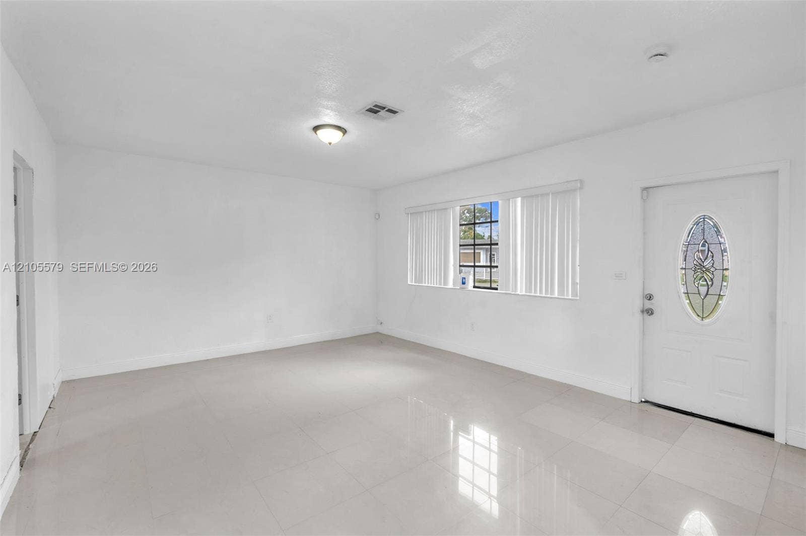 1750 NW 185th Street, Miami Gardens, FL 33056 Neutral-toned tile flooring, large multi-pane windows, and an entry door featuring an oval decorative glass insert