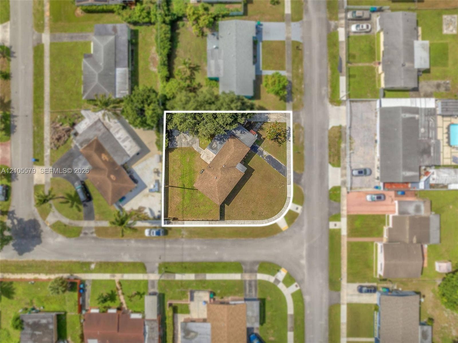 1750 NW 185th Street, Miami Gardens, FL 33056 Corner lot featuring a multi-pitched shingled roof, paved driveway, and established trees within the fenced perimeter