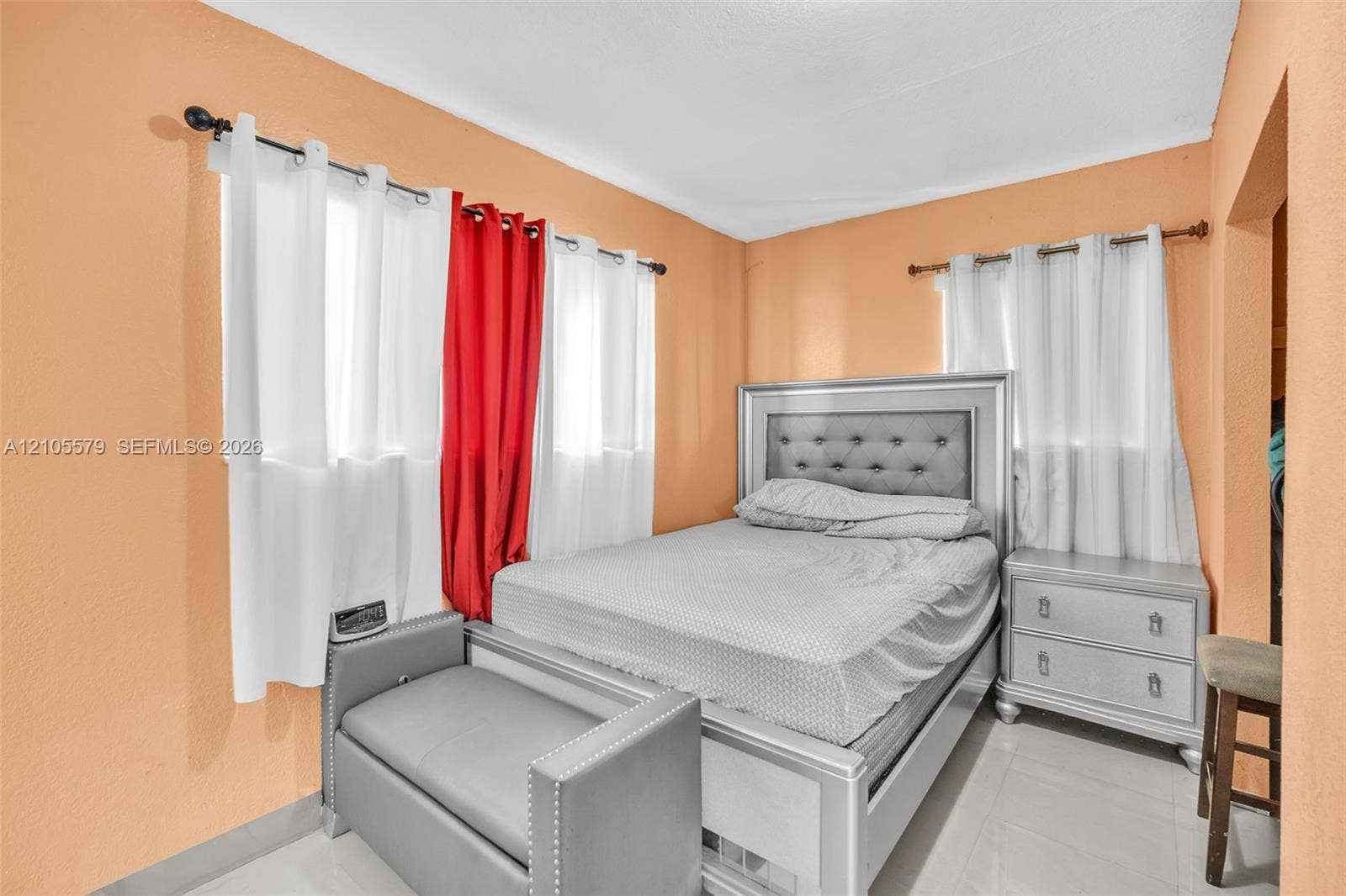 1750 NW 185th Street, Miami Gardens, FL 33056 Bedroom with dual-aspect windows, white-finished rod hardware, and light-colored tile flooring