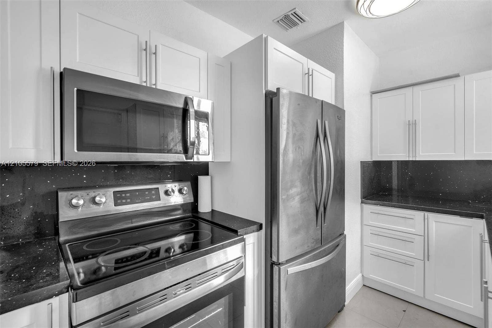 1750 NW 185th Street, Miami Gardens, FL 33056 Kitchen featuring white shaker-style cabinetry, stainless steel appliances, dark stone countertops, and a glass cooktop range