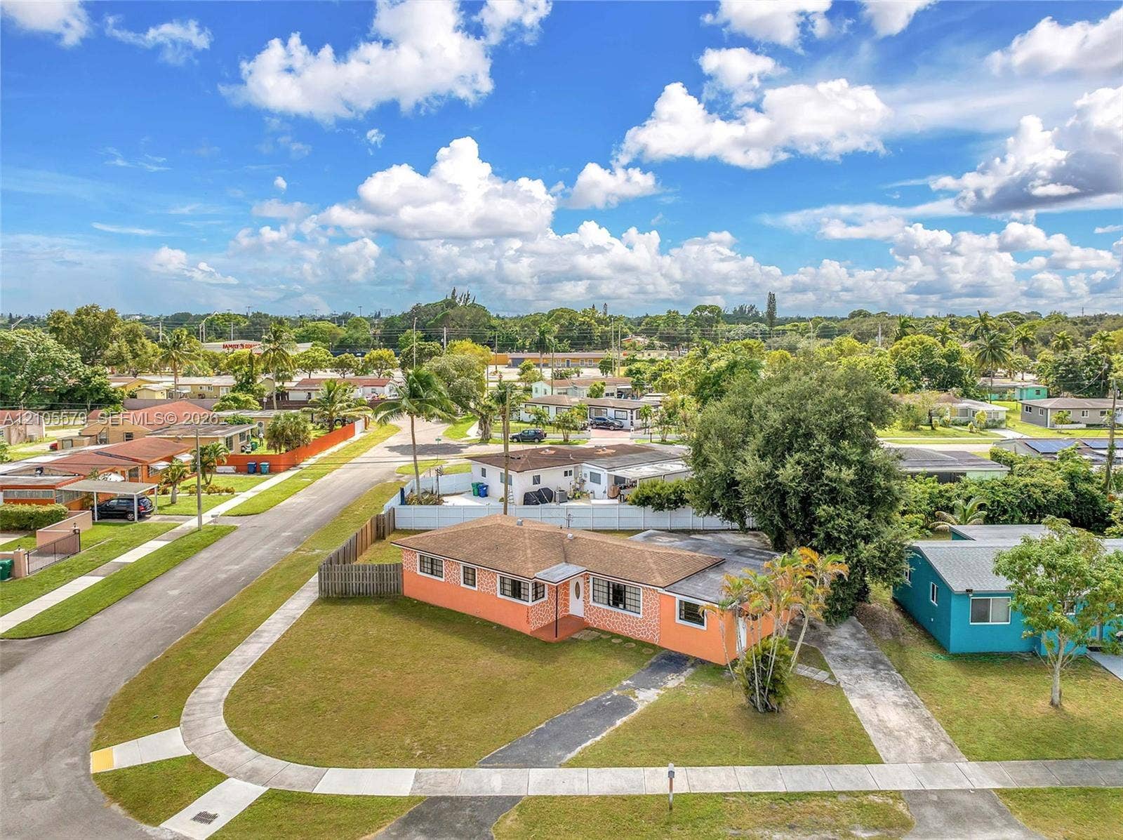 1750 NW 185th Street, Miami Gardens, FL 33056 Single-story residence featuring a hipped roof, brick-veneer exterior, concrete driveway, and mature landscaping