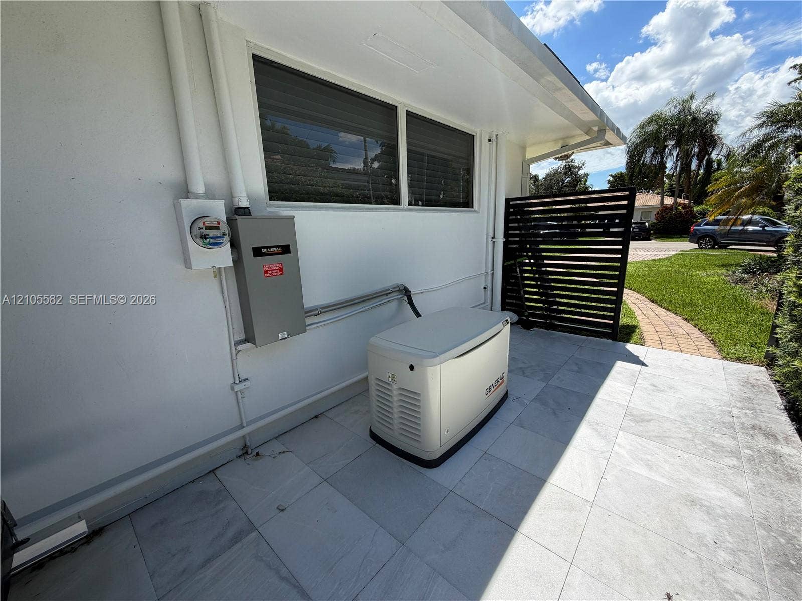 2215 NE 204th Street, Miami, Miami, FL 33180 Exterior wall with a Generac standby generator, a service meter, and a primary electrical panel