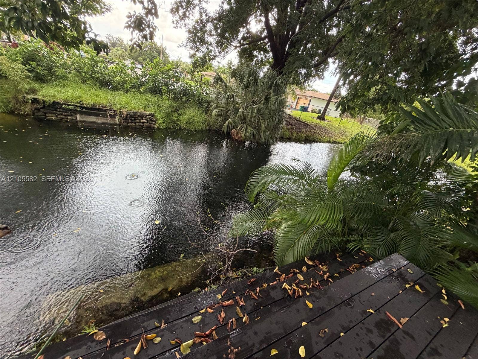 2215 NE 204th Street, Miami, Miami, FL 33180 Waterfront property featuring a wood-finish dock and lush tropical landscaping