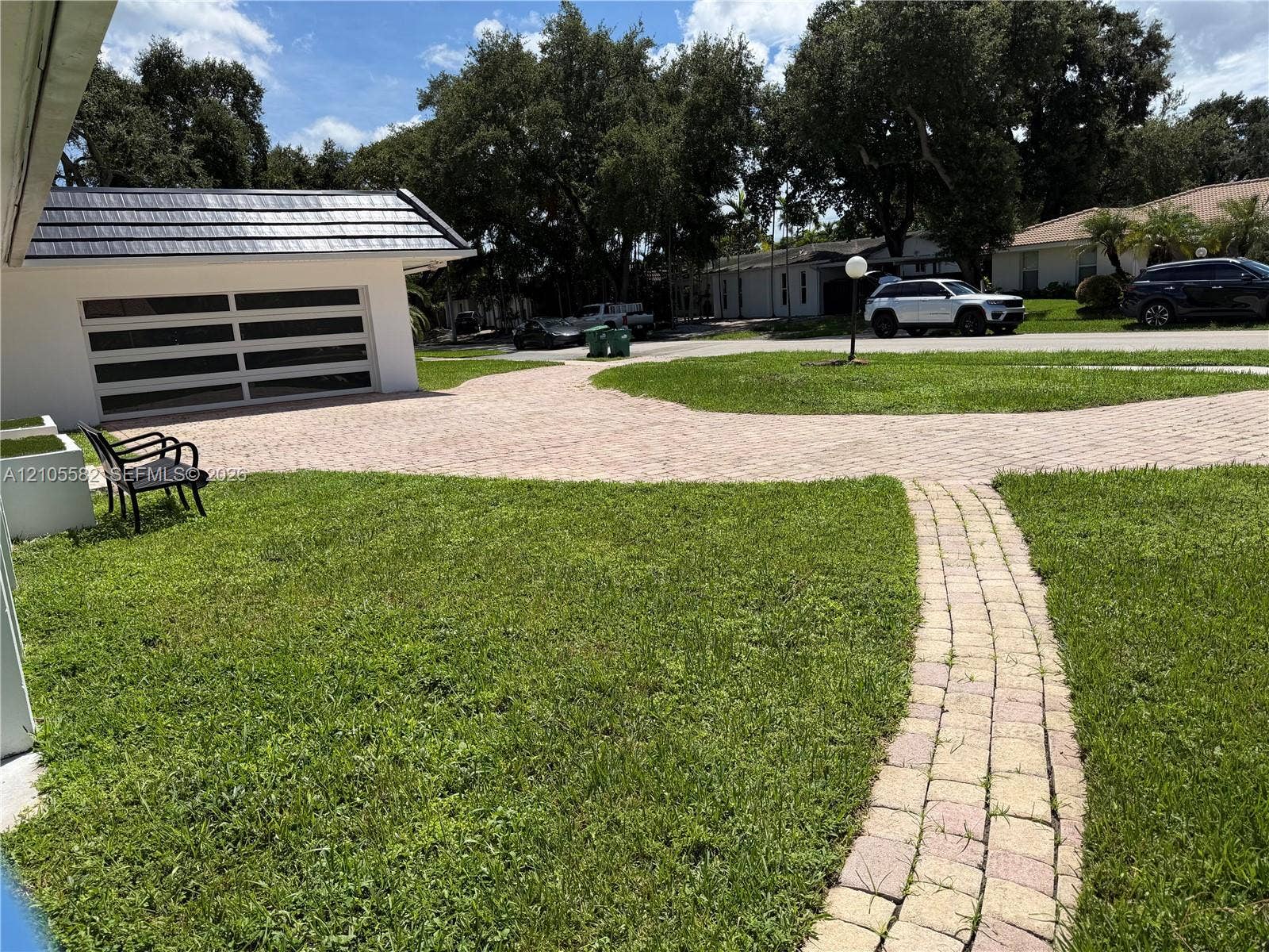2215 NE 204th Street, Miami, Miami, FL 33180 Paved driveway leading to a modern garage door with frosted glass panels, featuring a distinct dark-tiled roof