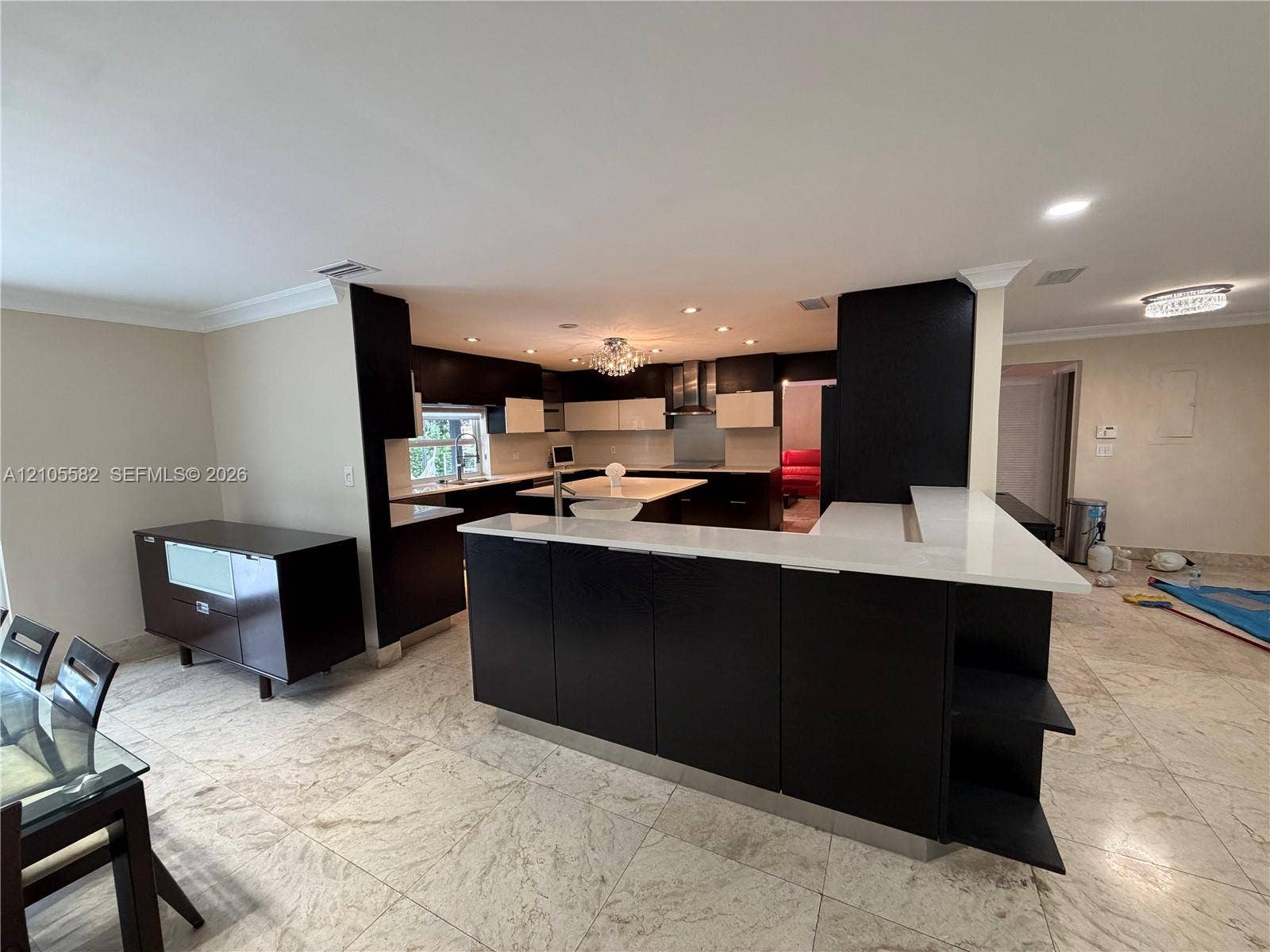 2215 NE 204th Street, Miami, Miami, FL 33180 Open-concept kitchen featuring an island with white countertops, dark wood-finish cabinetry, recessed lighting, and tile flooring throughout